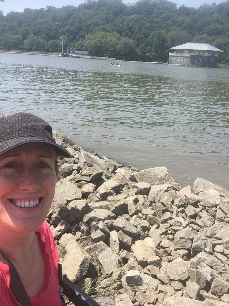 Cathy Boyle Almeida on the shore of The Harlem River as it runs along Roberto Clemente park